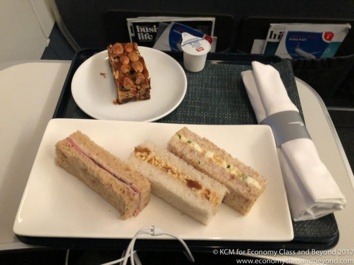 a plate of sandwiches and a piece of cake on a tray