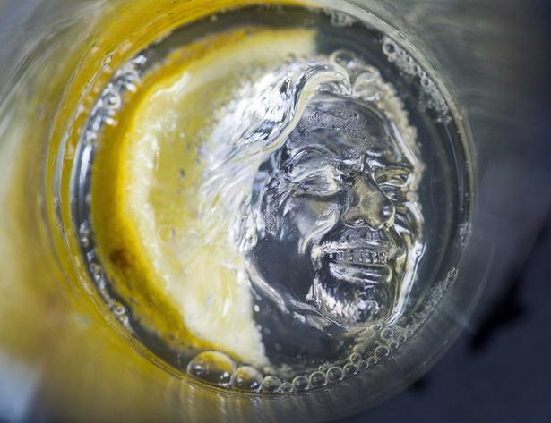 a silver head in a glass of water with a lemon slice