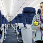 a woman standing in an airplane with a bunch of flowers