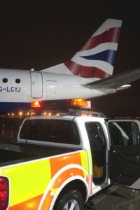 a white truck with a red and blue tail light on top of a plane
