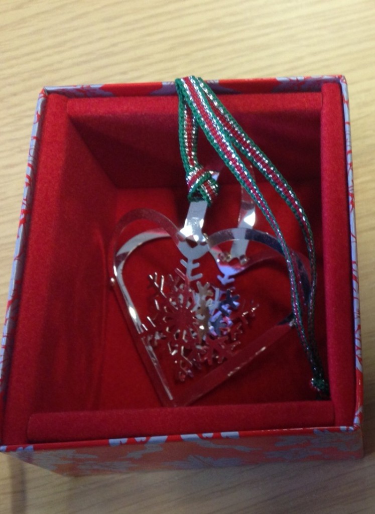 a silver heart shaped ornament in a red box