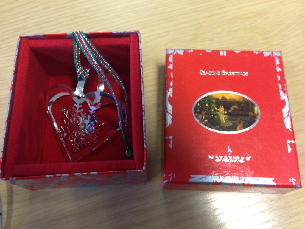 a red box with a silver heart shaped ornament in it