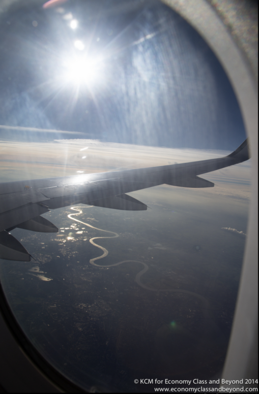 a wing of an airplane flying over a river