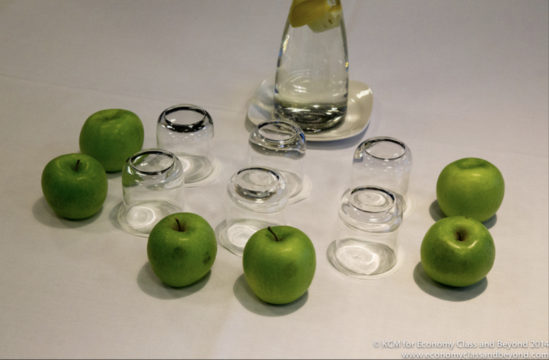 a group of green apples next to a glass of water