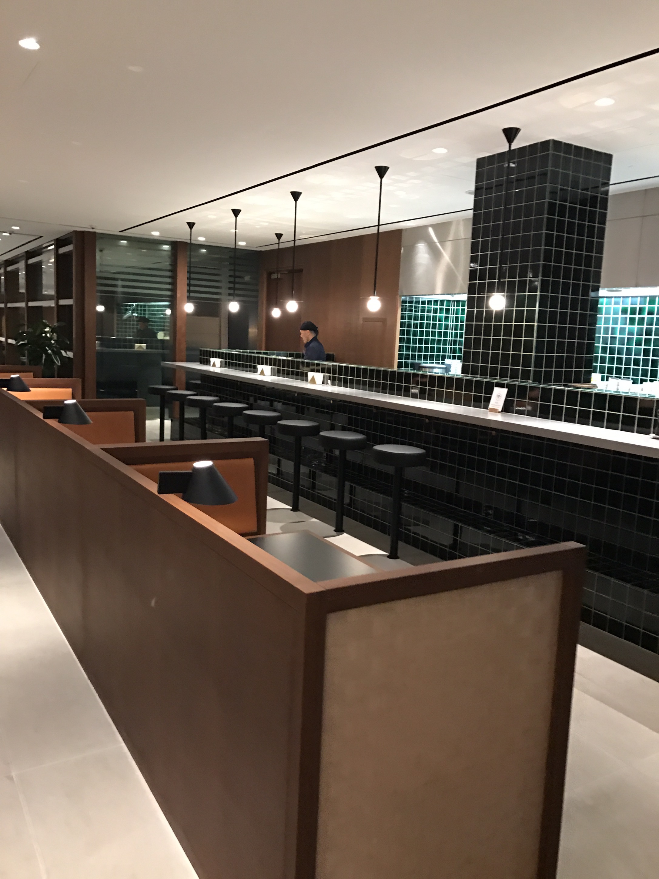a restaurant with a long counter and black tile walls