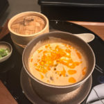a bowl of soup with a spoon and a container of food