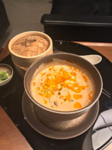 a bowl of soup with a spoon and a container of food