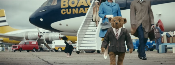 a teddy bear walking by a plane