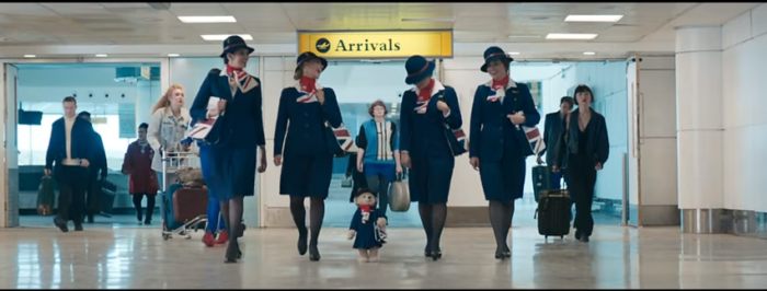 a group of women in blue uniforms walking in an airport