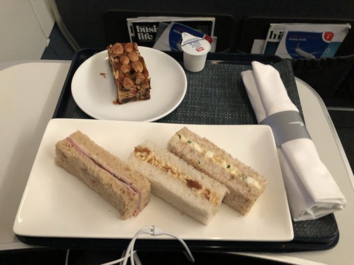 a plate of sandwiches and a piece of cake on a tray