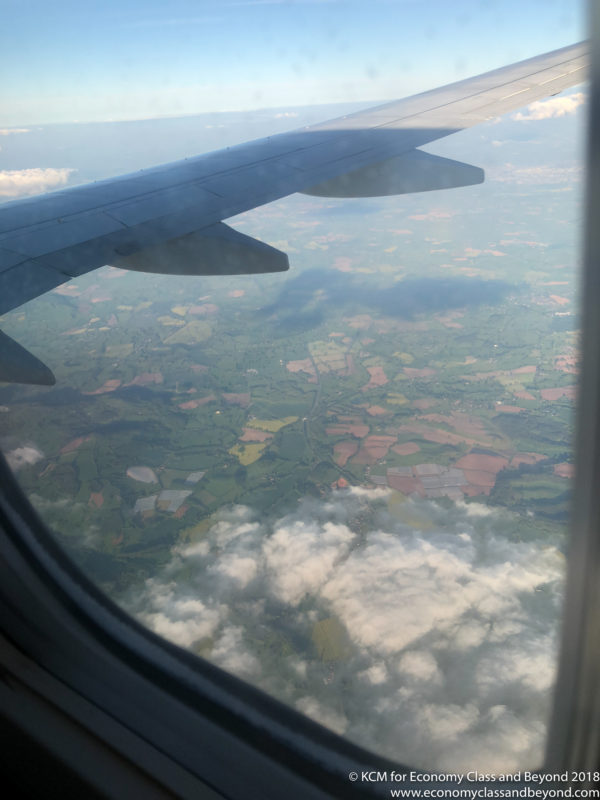 an airplane wing and view of land and clouds
