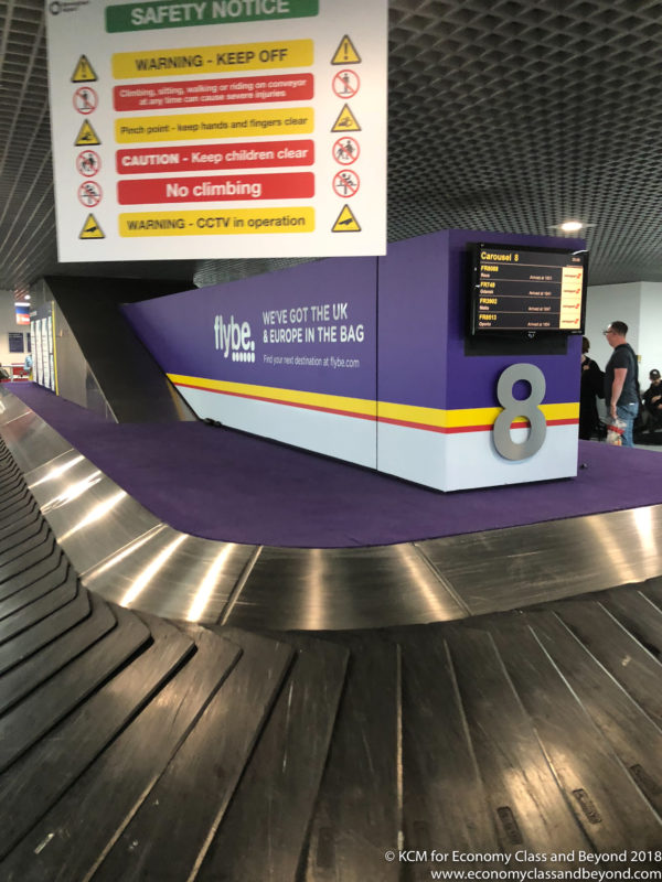 a luggage conveyor belt with signs and a sign on it