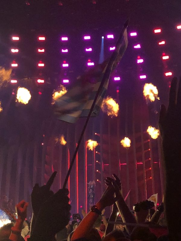 a group of people holding a flag in front of a stage with lights
