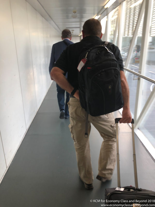 a man with a backpack walking down a hallway with a man in a suit
