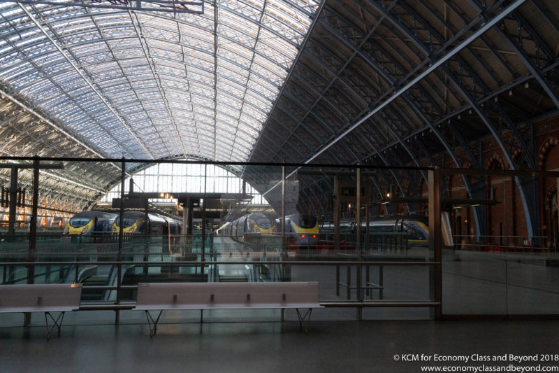 a train station with glass walls and a bench