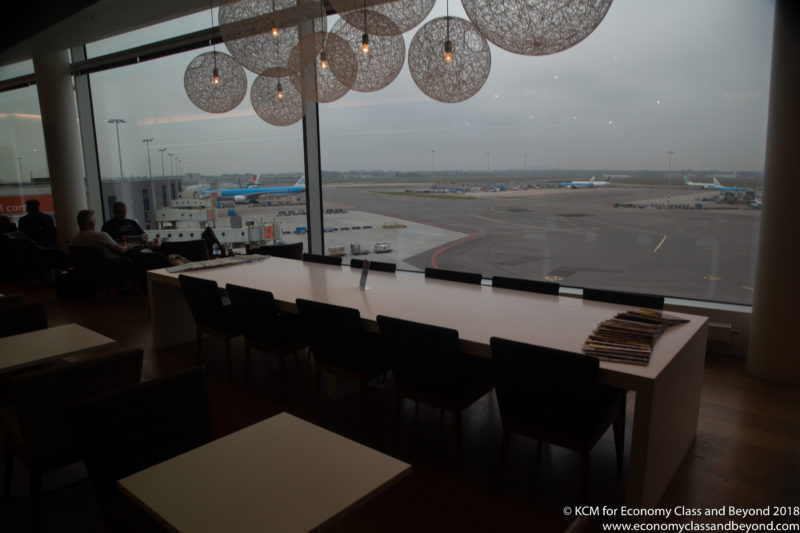 a long table with chairs and a large window with a view of an airport