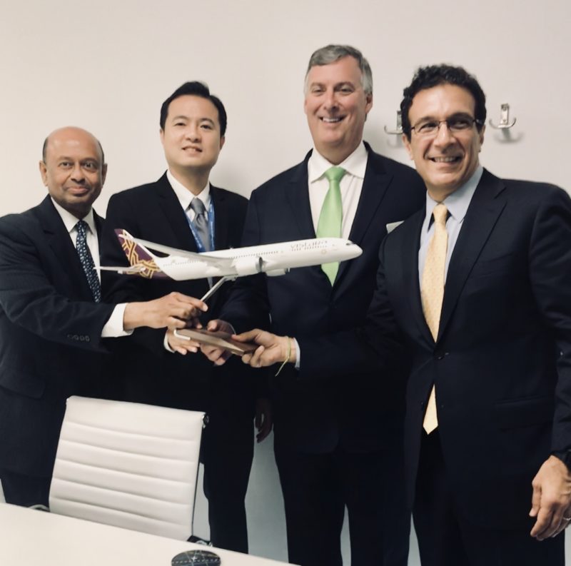 a group of men in suits holding a model airplane