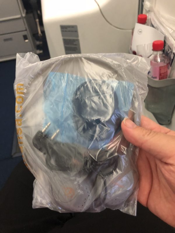 a hand holding a plastic bag with a black headphones in it