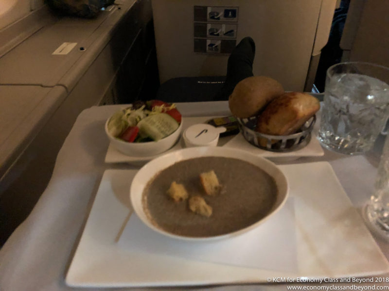 a bowl of soup and a bowl of bread on a tray