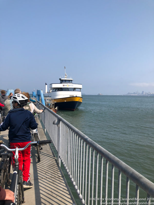 people on bicycles on a dock with a boat in the background