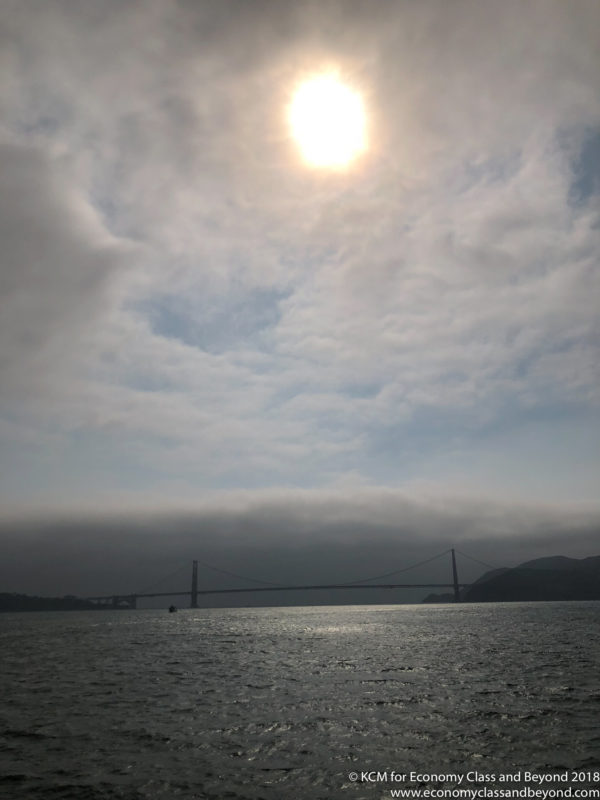a bridge over water with the sun shining through the clouds