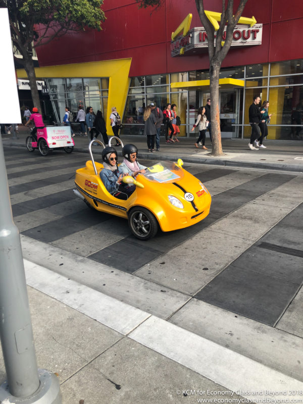 people in a small yellow car on a street