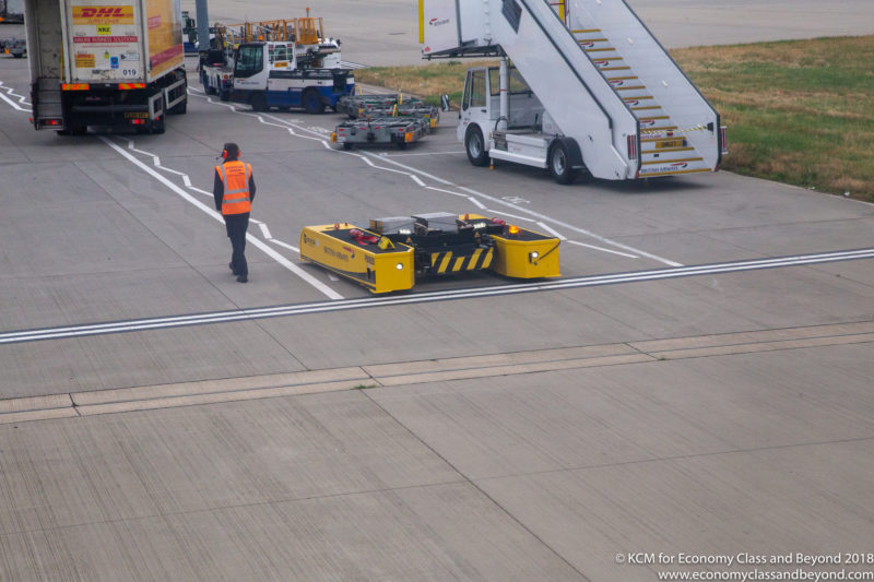 a man walking on a runway with a yellow vehicle