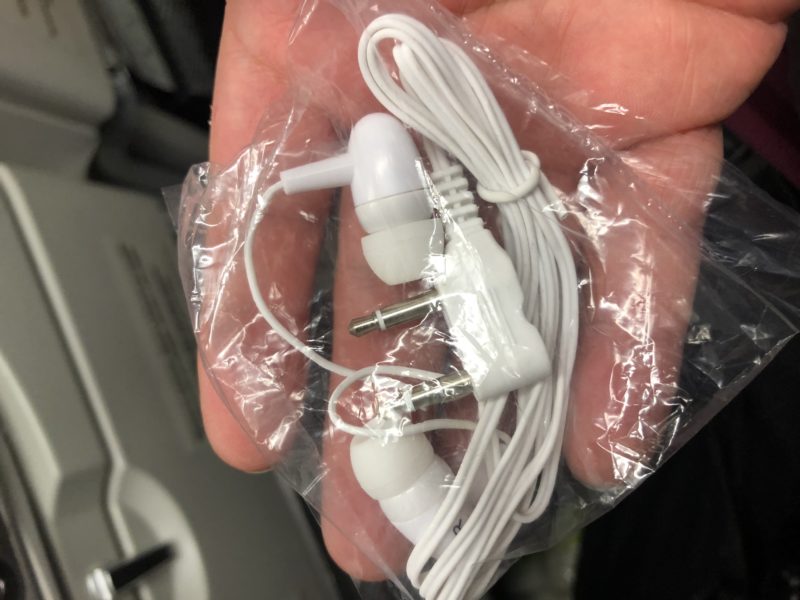 a hand holding a white earbuds in a plastic bag