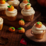 a group of cupcakes with frosting and small pumpkins