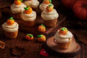 a group of cupcakes with frosting and small pumpkins