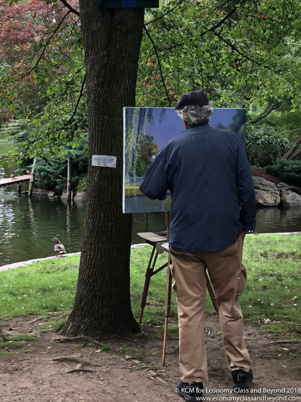 a man painting a picture on a easel