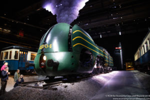 a green train on tracks with smoke coming out of it