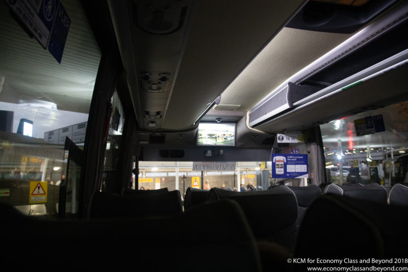 inside a bus with seats and a screen