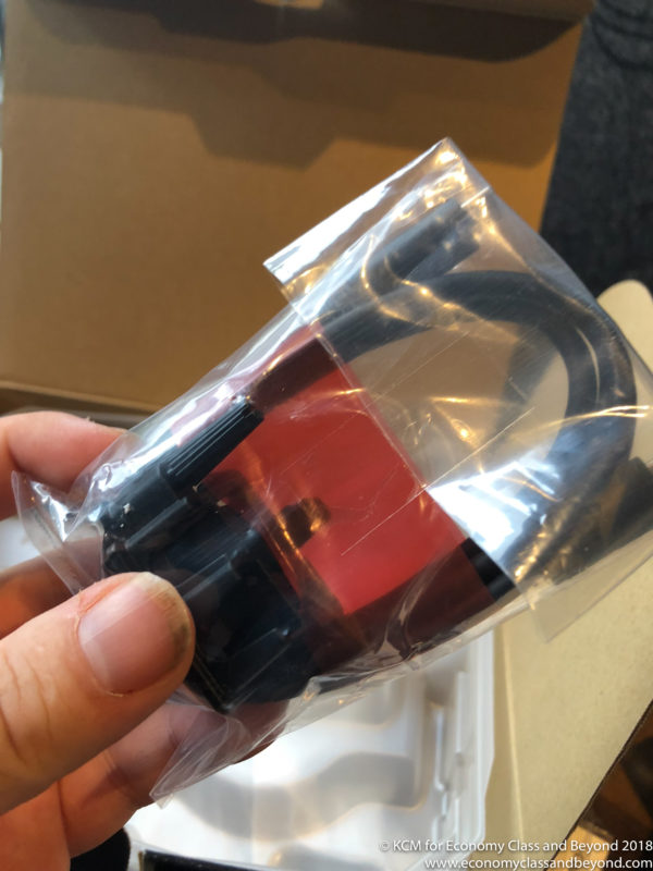 a hand holding a plastic bag with a red and black cable in it