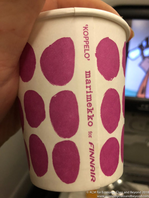 a hand holding a paper cup with purple dots