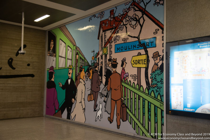 a mural of people walking on a train station