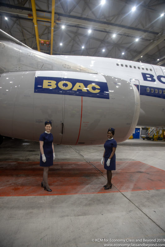 two women standing in front of a large airplane