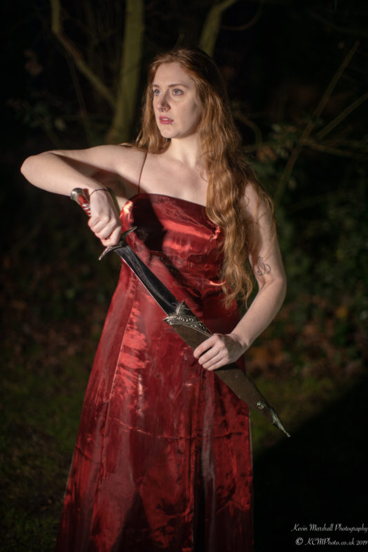 a woman in a red dress holding a sword
