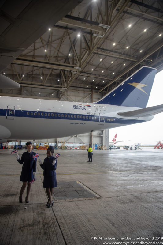 two women standing in a hangar with a plane