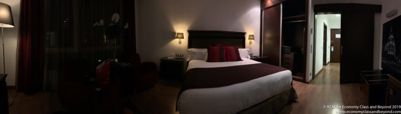 a bed with a brown headboard and red pillows
