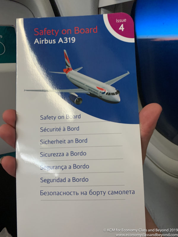 a hand holding a booklet with a picture of a plane