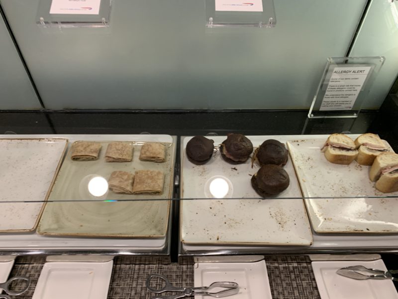 a trays of pastries and sandwiches on a glass shelf