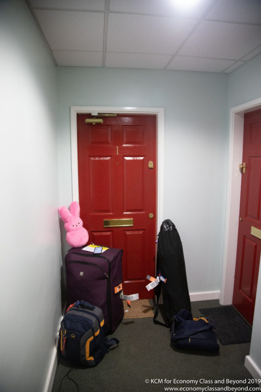 a red door with luggage and a stuffed bunny