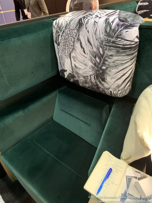 a green couch with a pillow and a pen