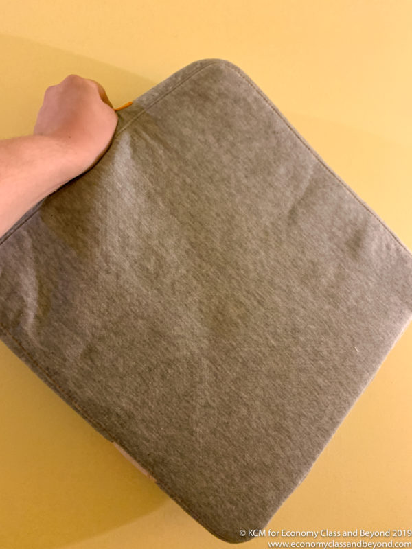a hand holding a grey fabric bag