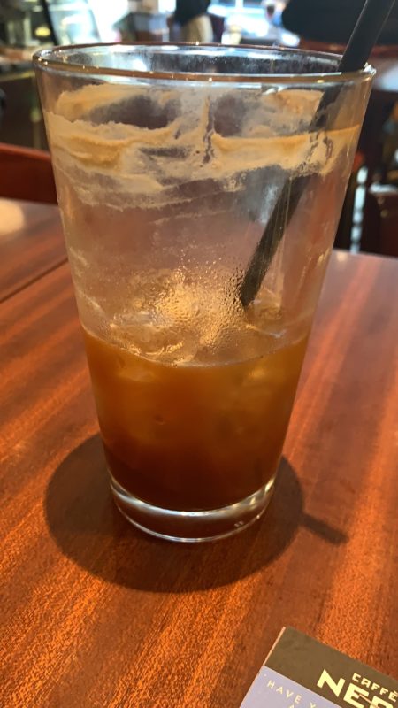 a glass of brown liquid with ice and a straw