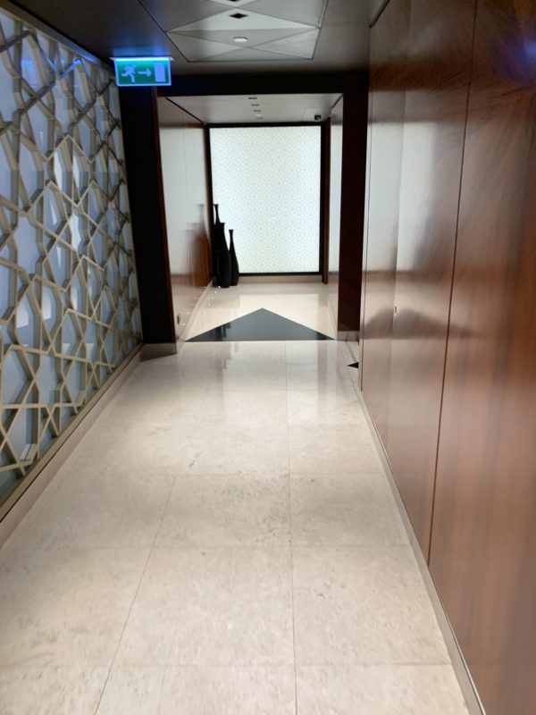 a hallway with a white tile floor and a black and white patterned wall