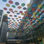 a multicolored umbrellas from the ceiling of a building