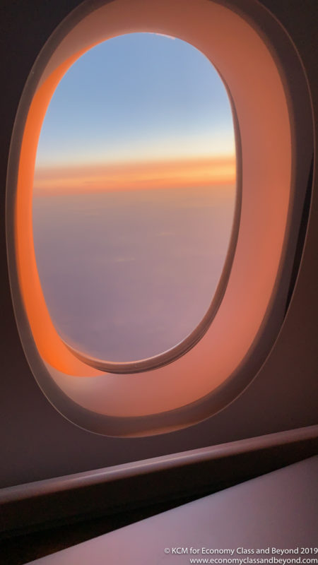 an airplane window with a sunset in the background