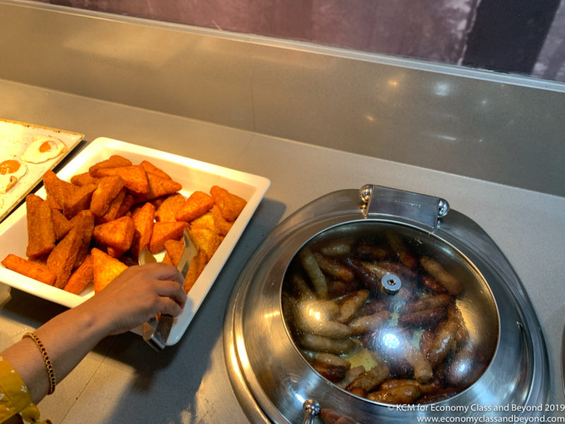 a person's hand reaching for food in a tray